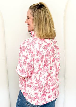 White top with pink floral pattern and v-neckline with contrast trim
