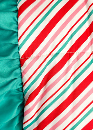 Holiday puffer vest with diagonal red, green, pink and white stripes. Snap closures, ruffle sleeves and front pockets.