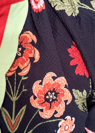 black button up long sleeve top with red flowers and greenery - red and green scalloped stripe detail along collar and down front 