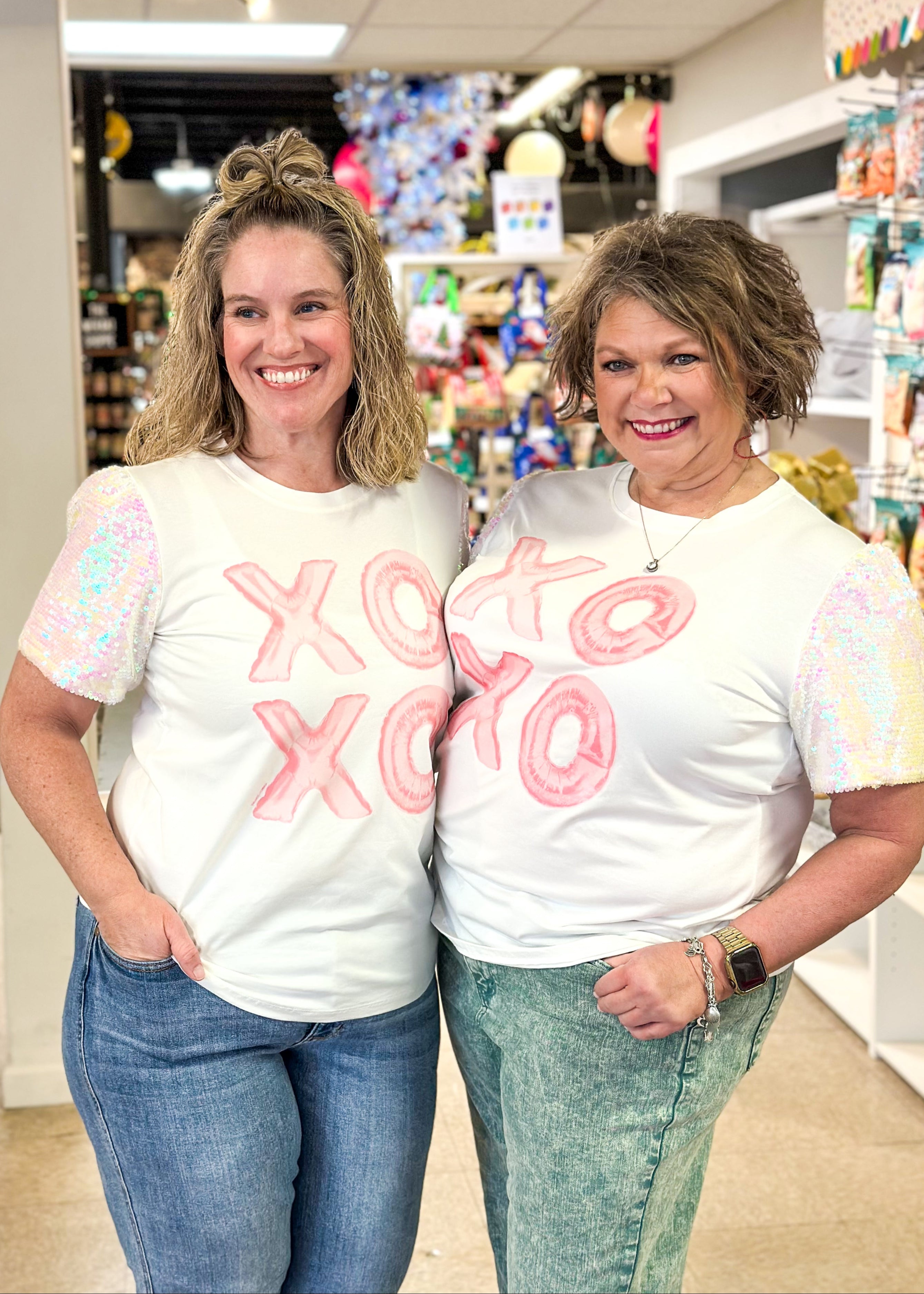 white short sequin sleeve top with XOXO in a light pink on the front - iridescent sequins on sleeves