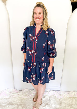Floral navy dress featuring v-neckline, burgundy piping, and puff sleeves