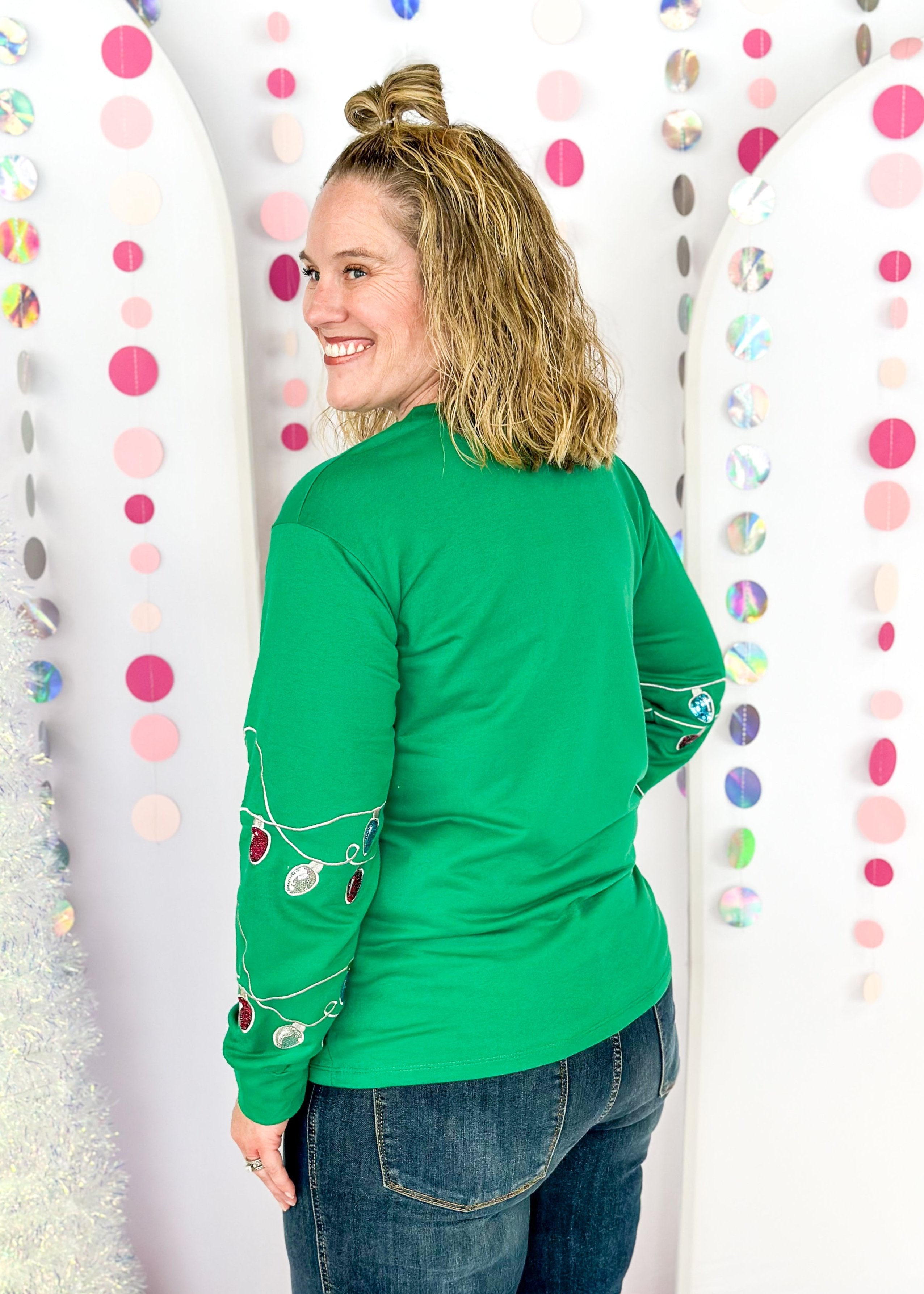 green long sleeve top with fa la la la la la across the front in sequin patches with sequin Christmas lights on the sleeves starting around the elbow down