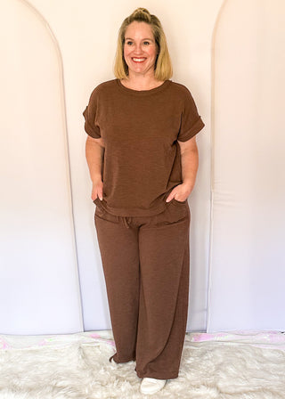 brown two-piece lounge set with relaxed short sleeve top and wide-leg drawstring pants.