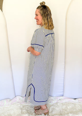 Blue and cream striped midi dress with short sleeves, split V-neckline with contrast trim, pockets, and a relaxed fit.