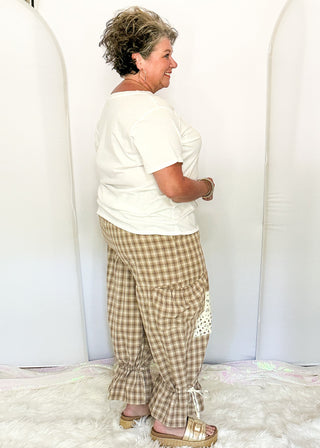 side view of woman modeling gingham bloomer pants with patches and pockets.