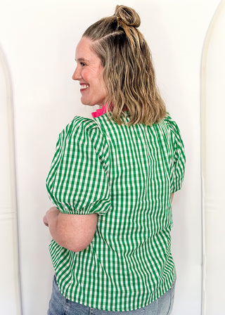 Women’s gingham blouse with decorative buttons and statement neckline detail.