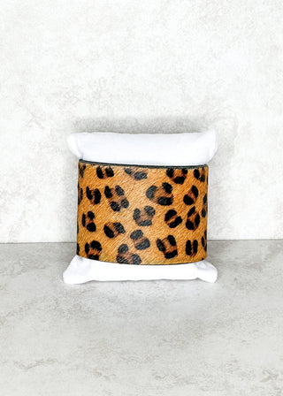 Leopard print cylindrical container on a white stand against a light gray background