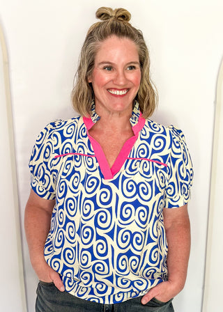Royal blue swirl print top featuring pink contrast trim, puff sleeves, and lightweight relaxed fit.