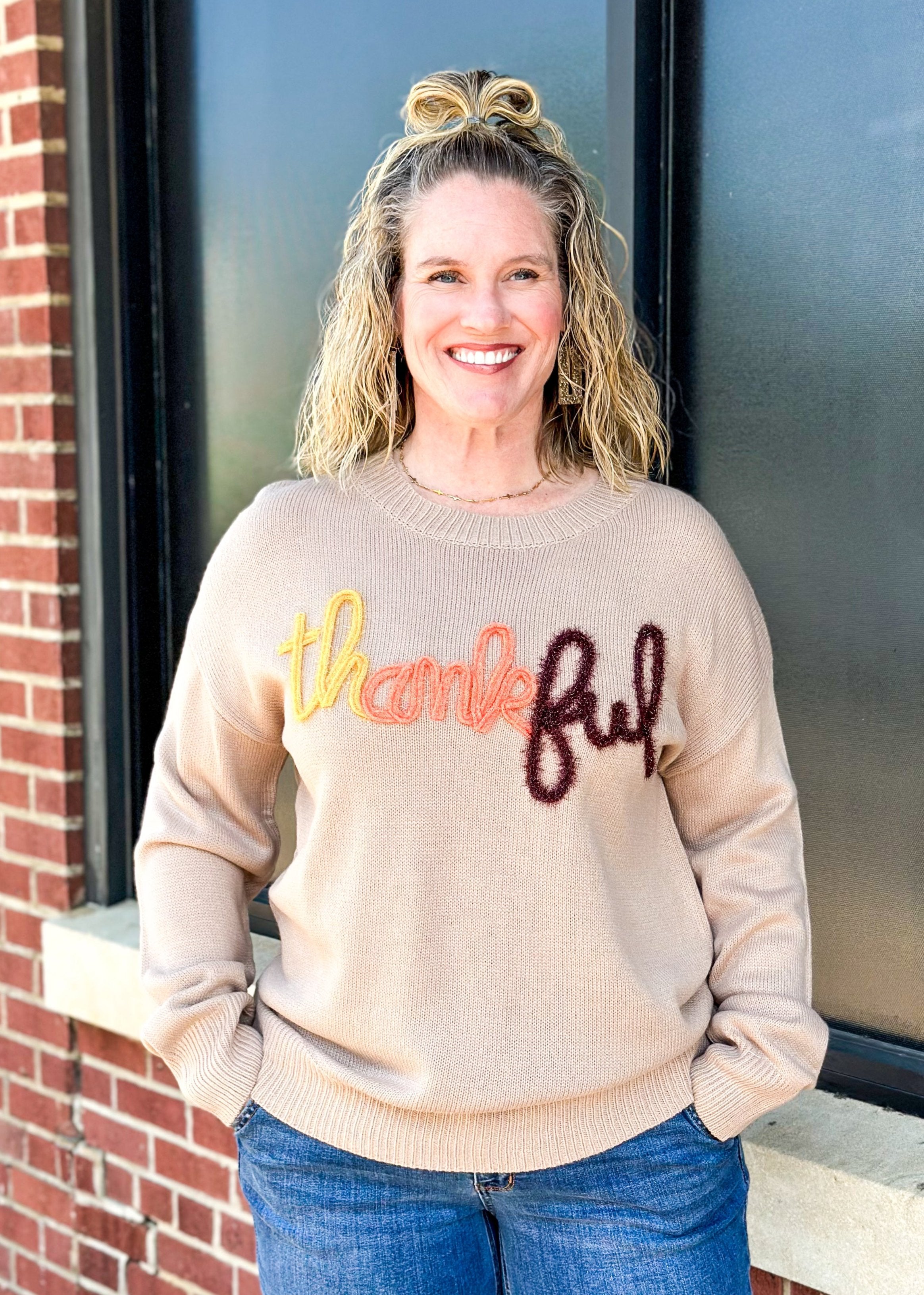 khaki long sleeve sweater with tinsel spelling out thankful across the front in yellow, orange and brown