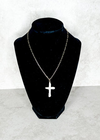 White beaded cross necklace on a black bust against a white background