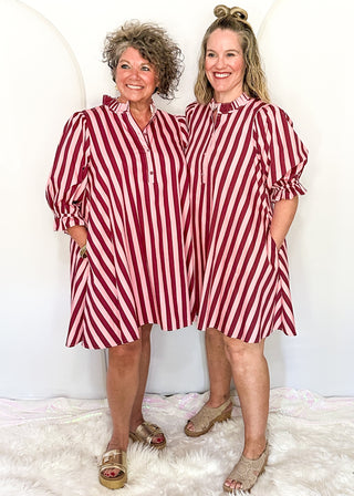 two models wearing pink and wine striped dress with pockets. 