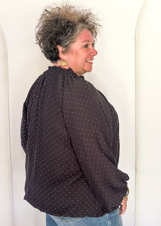 woman in black bubble hem long sleeve top with white dots.