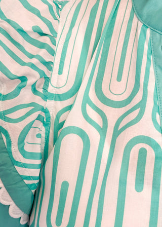 Close up of patterned short-sleeve top in mint with contrast trim with scallops, v-neckline.