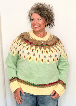 woman modeling a cozy long sleeve sweater with geometric pops of color with a cream and light blue base