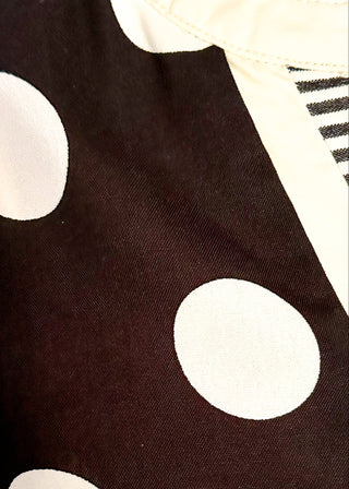 close up of women's black blouse with cream polka dots, striped split neckline, and flutter sleeves.