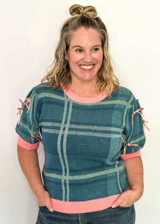 Turquoise plaid short sleeve sweater with pink trim and bow accents on the sleeves
