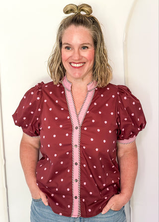 woman wearing burgundy button up top with polka dots.