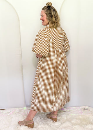 Woman wearing long brown gingham dress with short sleeves