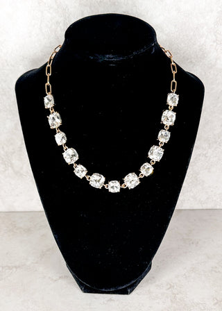Clear gemstone necklace displayed on a black neck form 