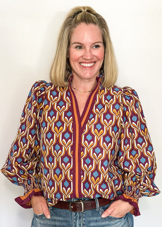 Wine-colored geometric print blouse with long puff sleeves and smocked cuffs.