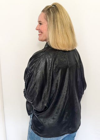 Shimmer black V-neck blouse with relaxed elastic short sleeves and a split hem at waist. 