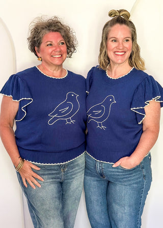 models in blue ruffle sleeve sweater with white stitched bird