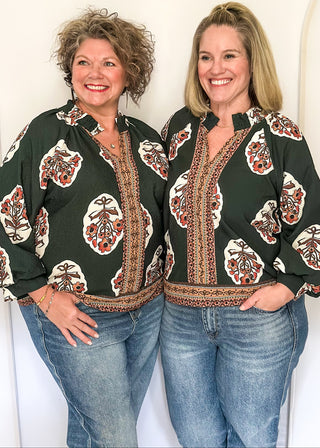 Forest green boho print top featuring smocked collar large floral bundles and colorful border trim.