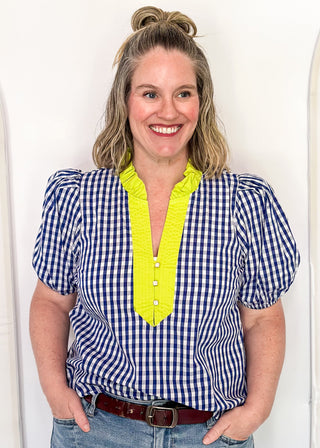 Women’s gingham blouse with decorative buttons and statement neckline detail.
