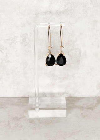 Teardrop gemstone dangle earrings in black. Displayed on a stand 