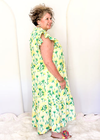 Women’s flowy maxi dress with green and yellow floral pattern and ruffle sleeve detail.