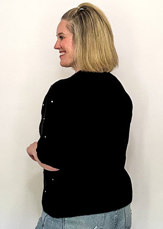 side view of woman wearing black sweater with rhinestones