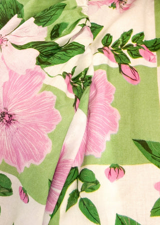 Close up of green and white checkerboard top with pink florals.  v-neck with decorative tassel detail and triple button.