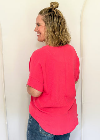 Solid pink textured blouse with a V-notch neckline, short sleeves
