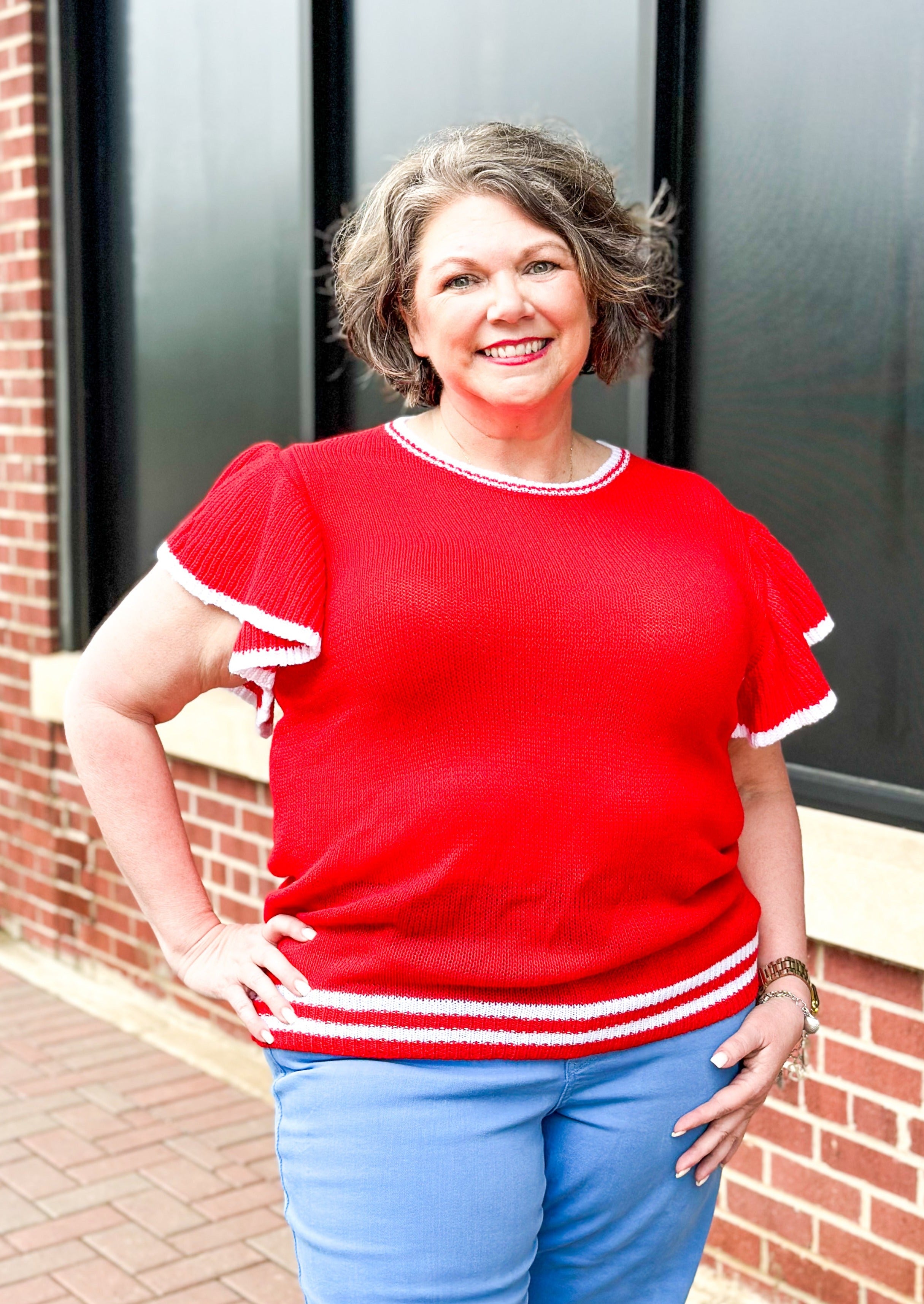 Short flutter sleeve red sweater with white trim around sleeve, neckline and bottom