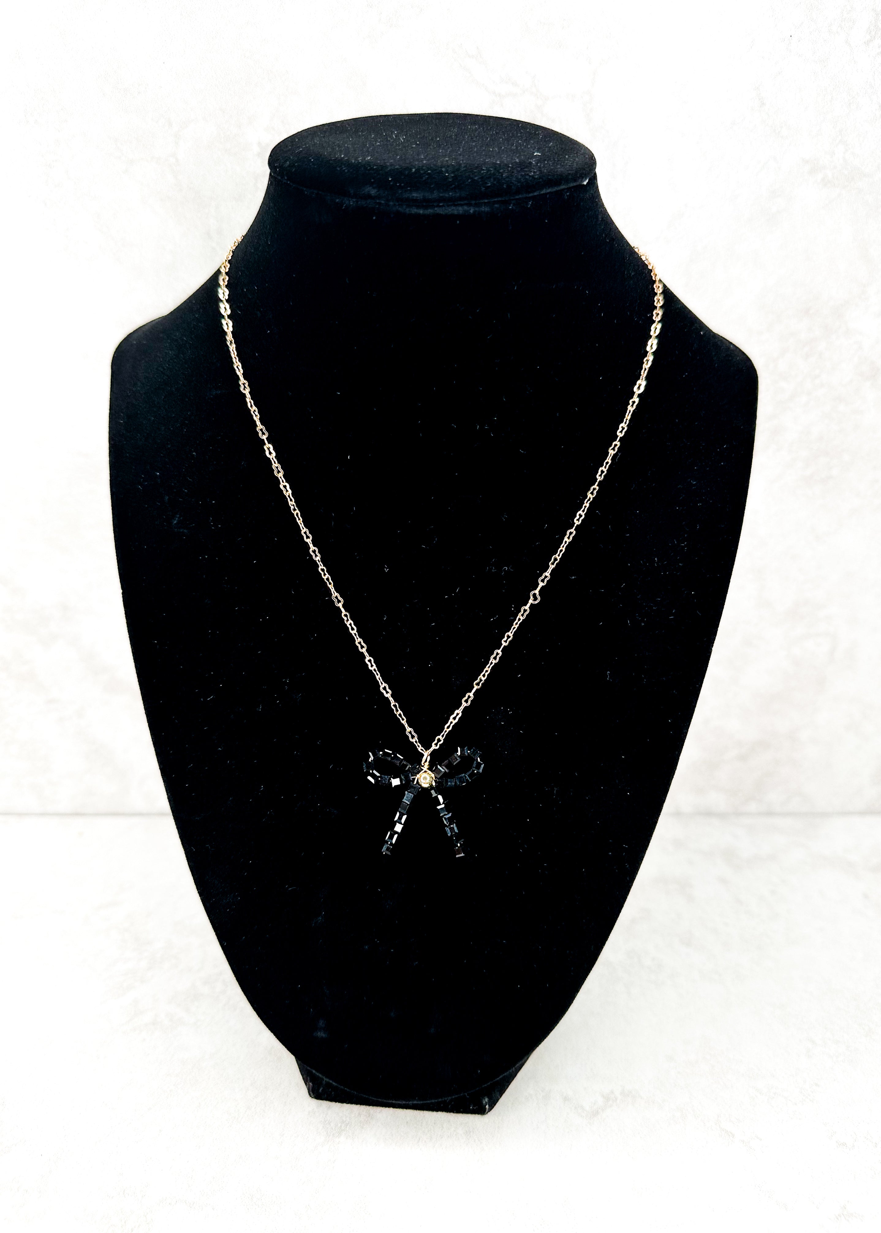 gold chain necklace with white beaded bow pendant