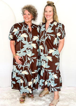 Two women standing in a brown, soft blue and off white floral midi dress.