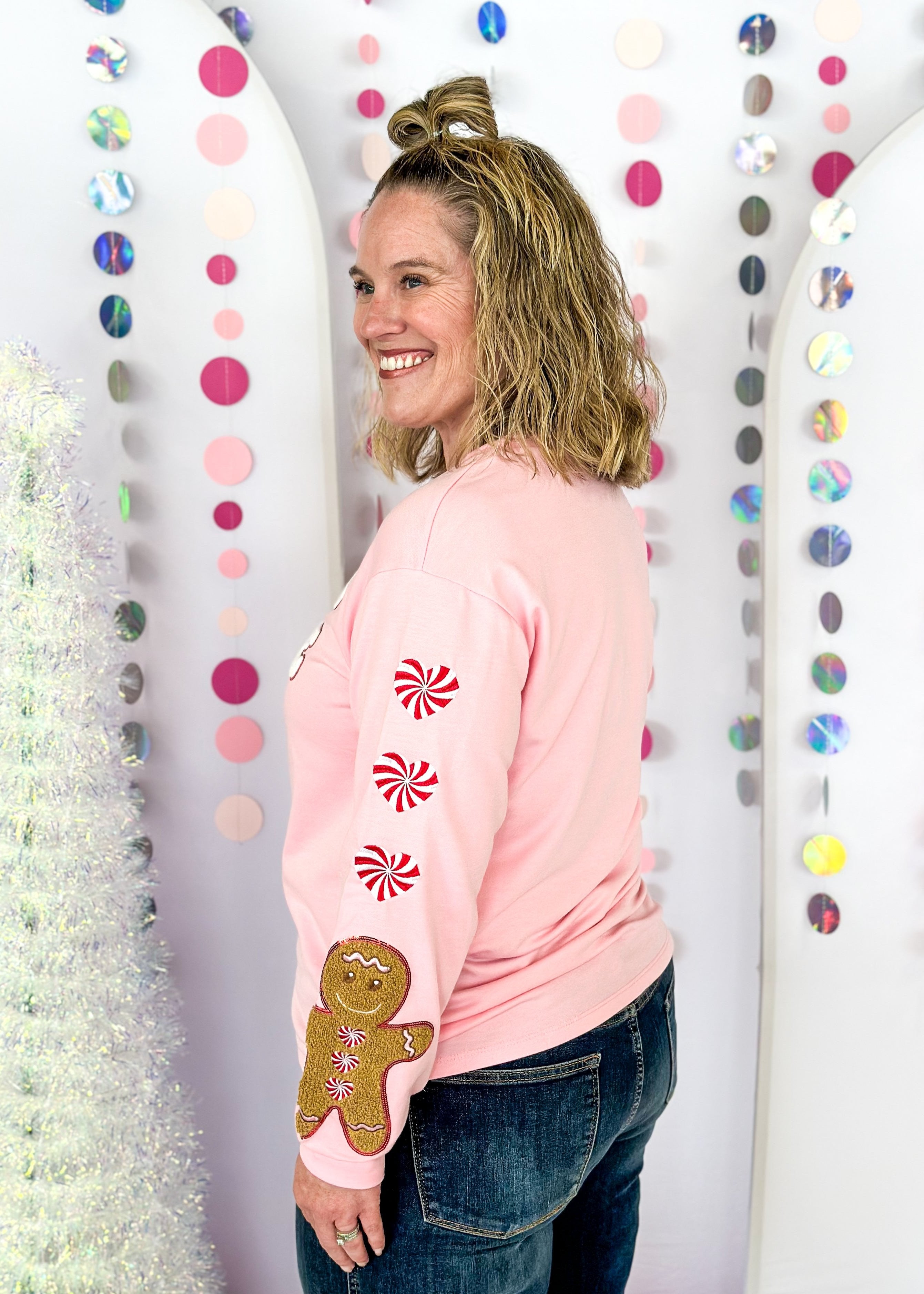 pink long sleeve top with feelin' festive patches across the front - heart shaped peppermint patches down the sleeve with one gingerbread man patch at the bottom of each sleeve