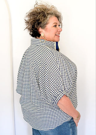 Navy check pattern blouse with contrast white stitching, short dolman sleeves, relaxed shape, and v-split neckline.