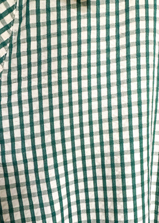 Close-up of a green and white gingham checkered fabric, showing the pattern and texture of the material.