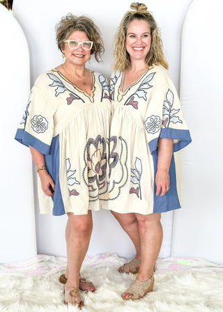 v-neck dress in cream with dusty blue on the side and arm at the edge - large floral print embroidery throughout - above the knee in length