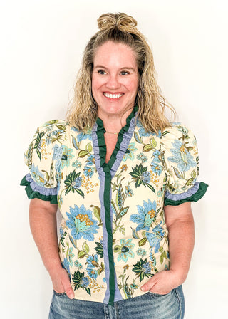 light blue and dark green botanicals on an ecru background.  Short ruffle sleeves, v-neck ruffle collar.  