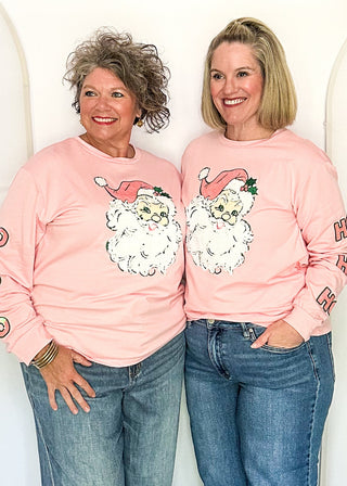 Two women modeling a soft pink long sleeve top with sequin Santa face on the front and HO HO HO on the sleeves. 