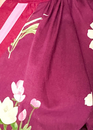 Plum top with florals in light pink and white with green leaves.  3/4 length sleeve and v-neck with contrast detail in plum and light pink. 