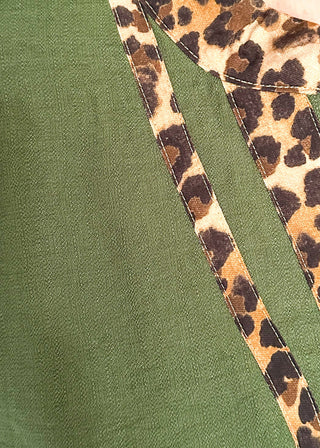 Close-up of a green top with a leopard-print collar and matching leopard-print trim running down the front.