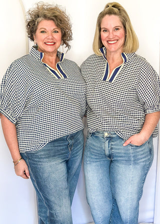 Navy check pattern blouse with contrast white stitching, short dolman sleeves, relaxed shape, and v-split neckline.