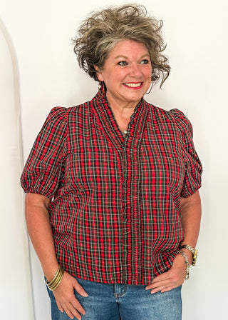 woman wearing a plaid puff sleeve top in red with short sleeves and a V-neckline.