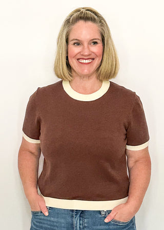 woman modeling a brown, short sleeve sweater with cream banding on sleeves, collar and hem.