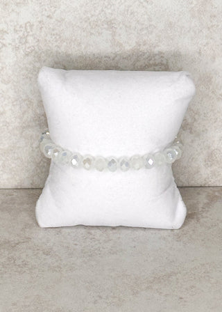 White iridescent beaded bracelet displayed on a stand 