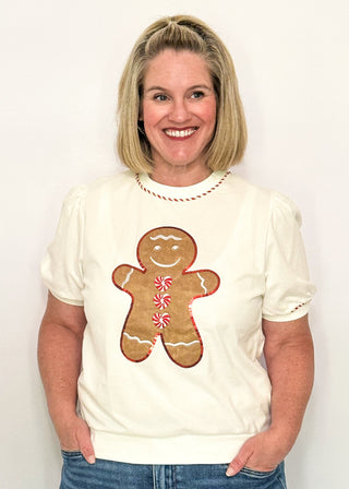 woman modeling a short sleeve puff sleeve top with fabric gingerbread man with sequins and embroidery details