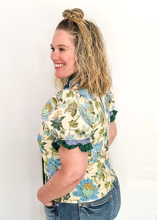 light blue and dark green botanicals on an ecru background.  Short ruffle sleeves, v-neck ruffle collar.  